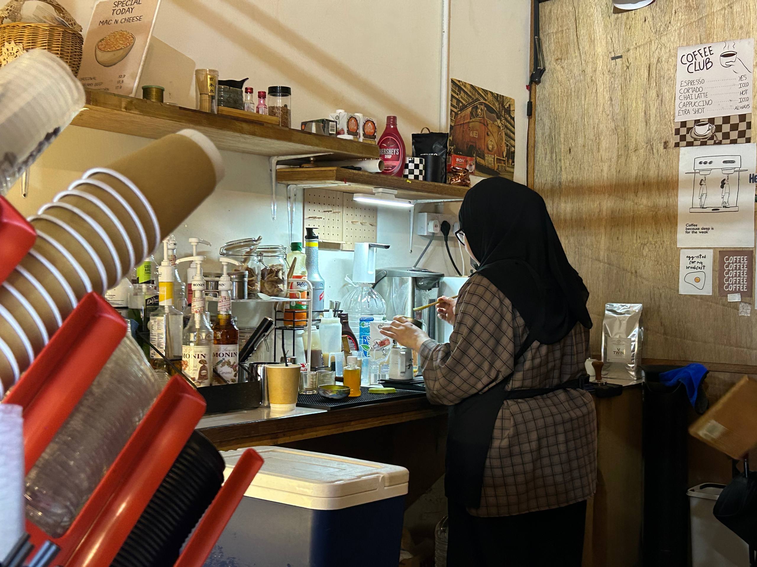 A barista preparing drinks at the compact timber coffee station.