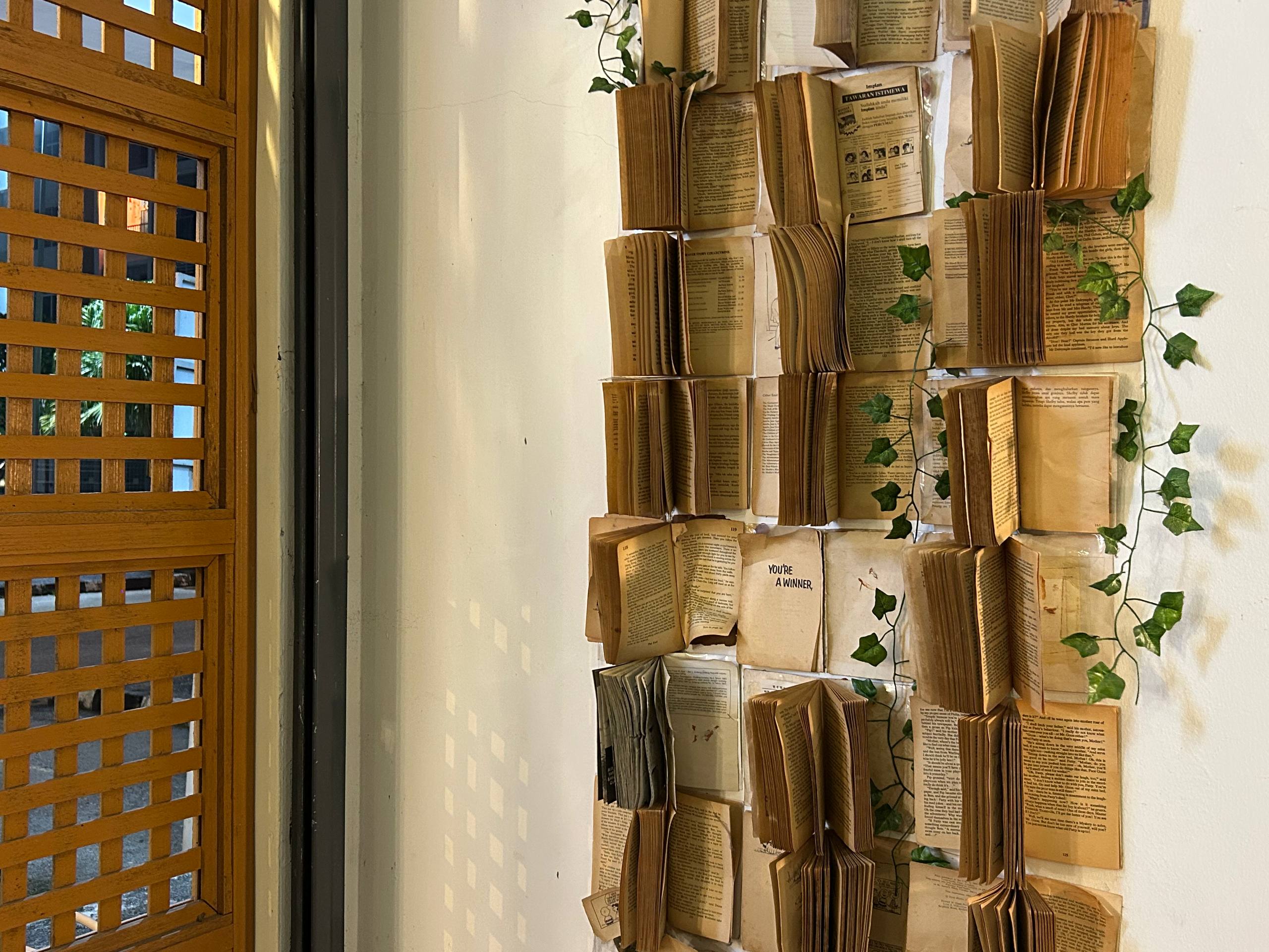 Open vintage books arranged as a wall installation beside a wooden lattice