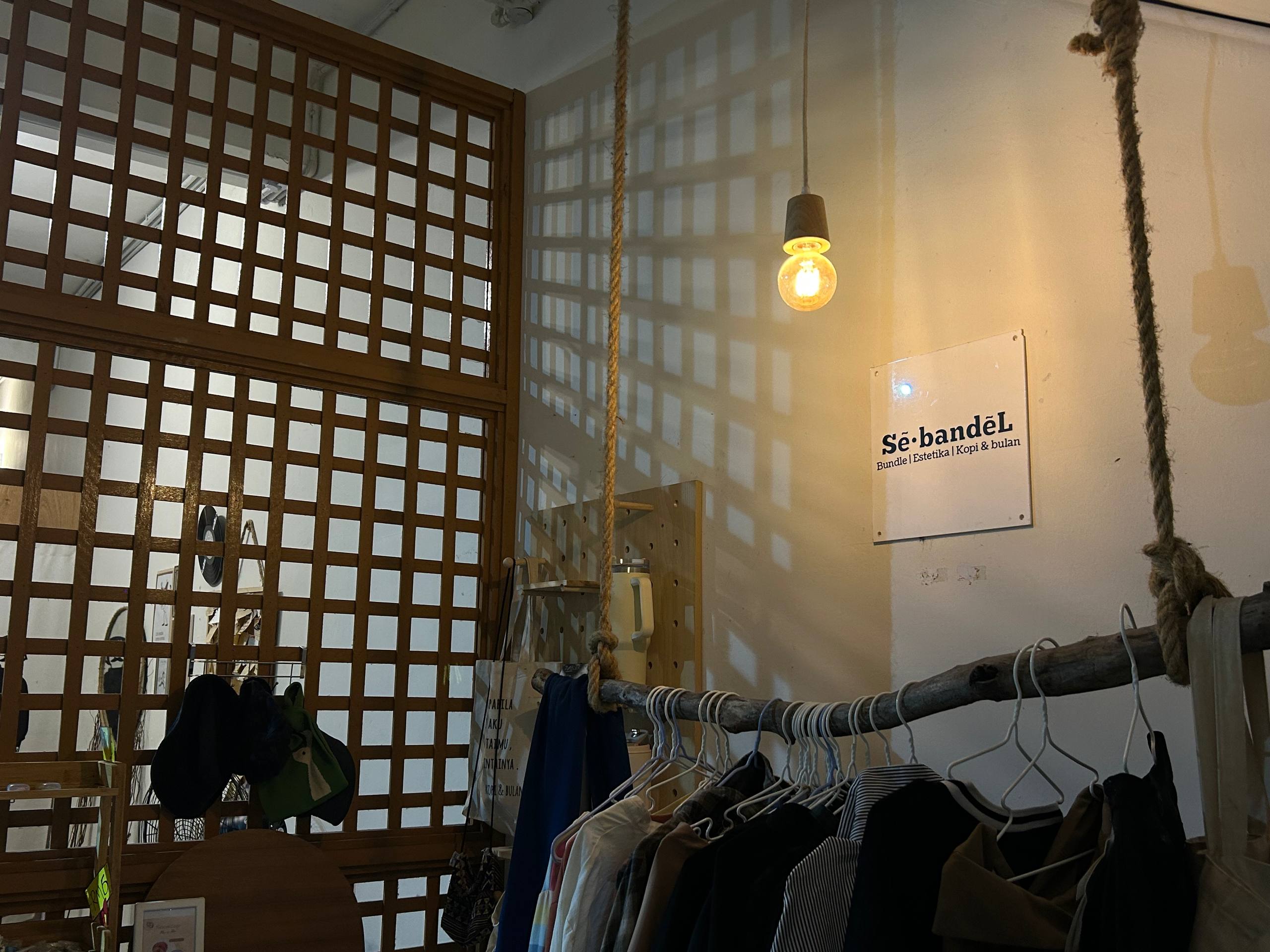 Warm hanging light beside the café timber lattice and clothing display